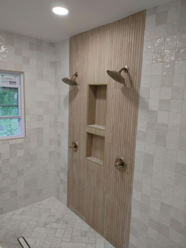 Dual rain shower heads mounted on a vertical wood panel with built-in niches in a tiled shower area.
